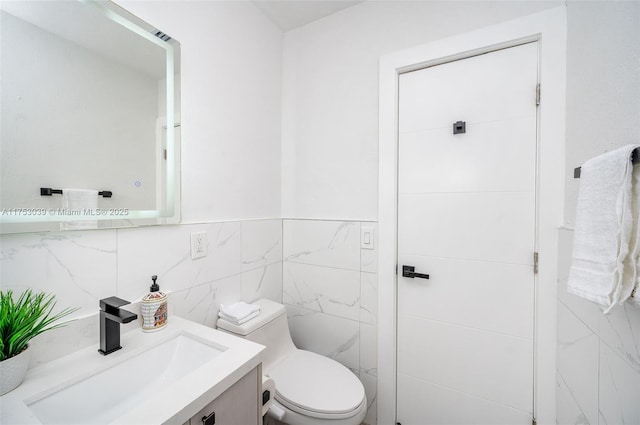 bathroom featuring toilet, tile walls, and vanity