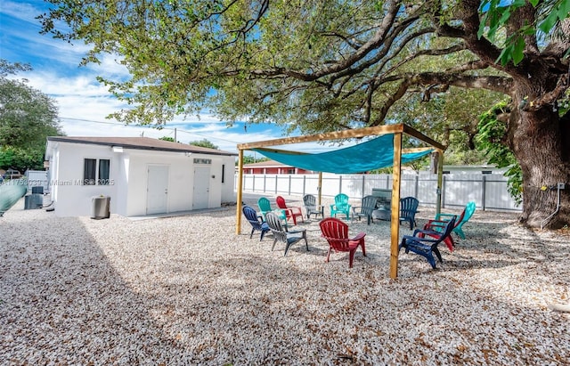 view of yard with an outbuilding, an outdoor fire pit, cooling unit, and fence