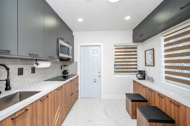 kitchen featuring marble finish floor, stainless steel microwave, a sink, and brown cabinets