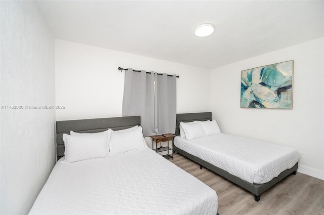 bedroom with baseboards and wood finished floors