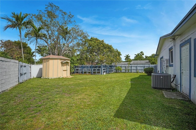 view of yard featuring an outbuilding, a shed, a fenced backyard, and cooling unit