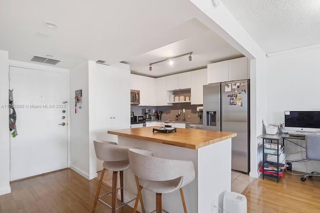 kitchen with a center island, appliances with stainless steel finishes, white cabinetry, a sink, and a kitchen breakfast bar