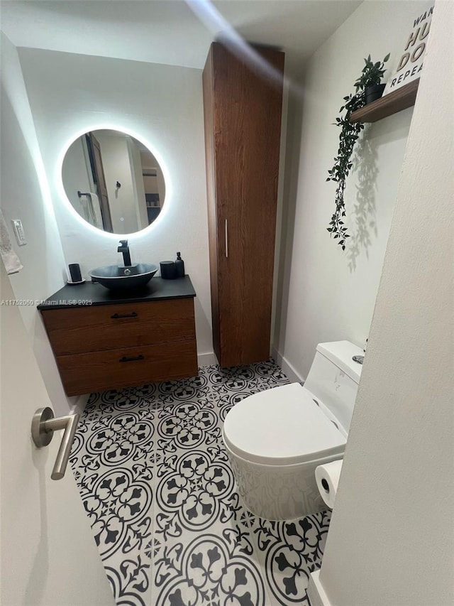 half bath featuring vanity, tile patterned flooring, toilet, and baseboards