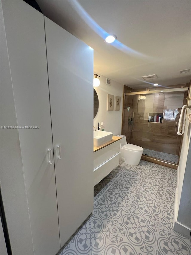 bathroom with tile patterned flooring, toilet, visible vents, vanity, and a shower stall