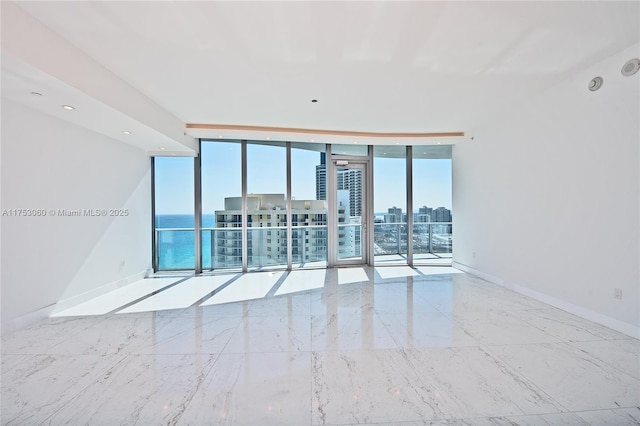 empty room with recessed lighting, a city view, baseboards, marble finish floor, and expansive windows