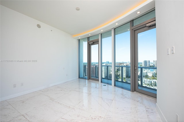 unfurnished room with expansive windows, marble finish floor, a view of city, and baseboards