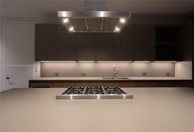 kitchen featuring stainless steel gas cooktop, extractor fan, modern cabinets, and a sink