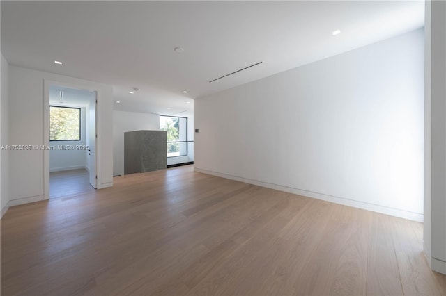 spare room featuring light wood-style flooring, baseboards, and a wealth of natural light