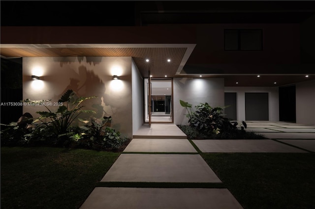 exterior entry at twilight featuring stucco siding