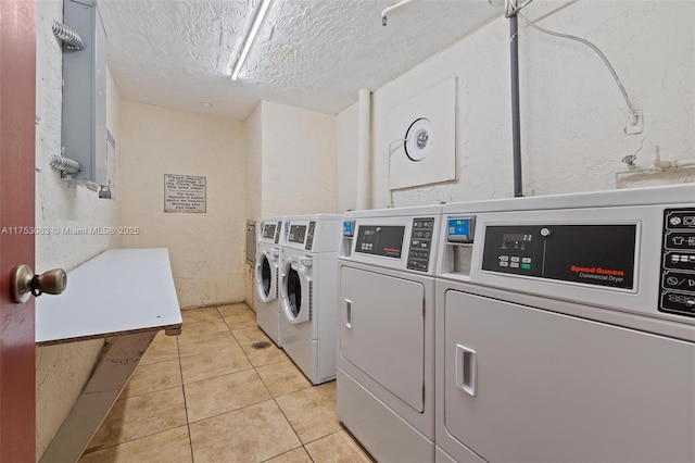 common laundry area featuring a textured wall, washer and clothes dryer, a textured ceiling, and light tile patterned floors