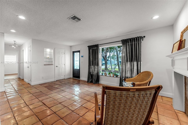 sitting room featuring a textured ceiling, light tile patterned flooring, recessed lighting, visible vents, and baseboards