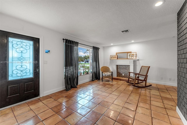 entrance foyer with a textured ceiling, light tile patterned floors, recessed lighting, visible vents, and baseboards