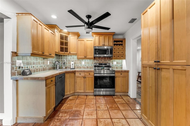 kitchen with visible vents, glass insert cabinets, a sink, stainless steel appliances, and backsplash