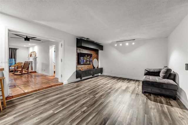 living area with visible vents, baseboards, ceiling fan, wood finished floors, and a textured ceiling