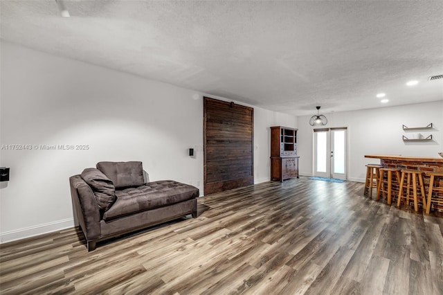 living area featuring a textured ceiling, baseboards, and wood finished floors