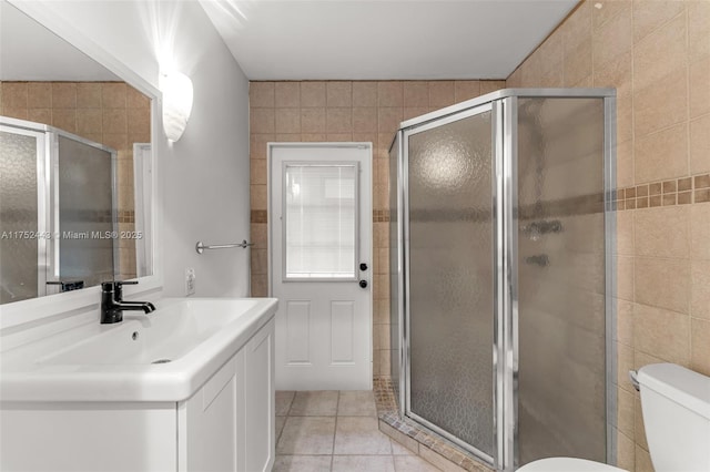 full bathroom with toilet, tile patterned flooring, a sink, and tile walls