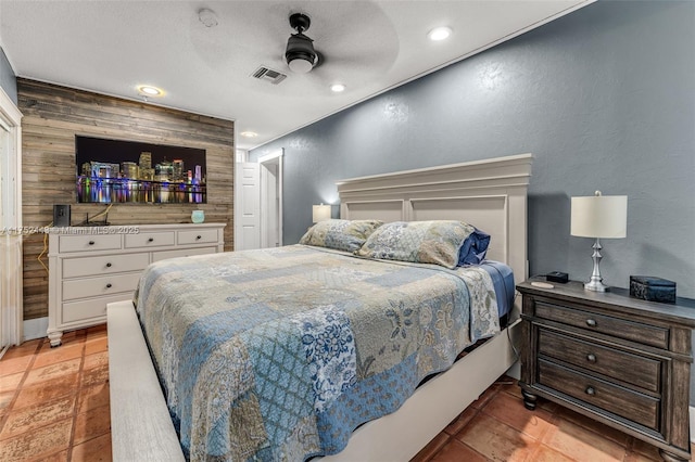 bedroom featuring a textured wall, recessed lighting, wood walls, a ceiling fan, and visible vents