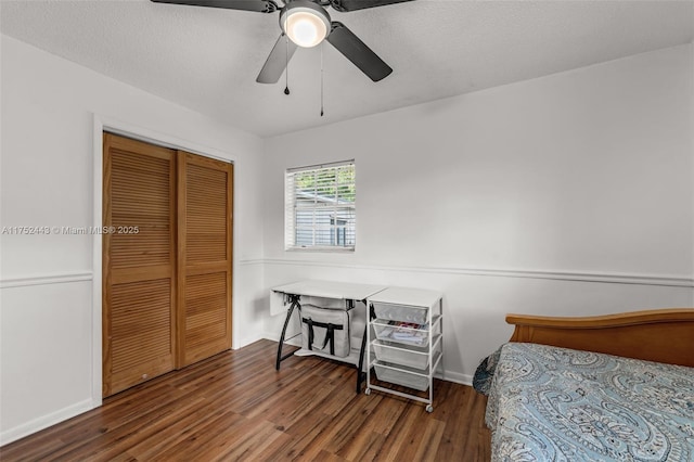 bedroom featuring a textured ceiling, dark wood-style flooring, a closet, and a ceiling fan