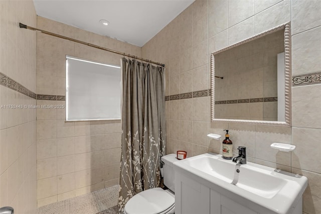 bathroom featuring toilet, vanity, a tile shower, and tile walls