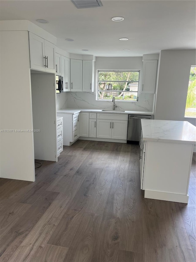 kitchen with decorative backsplash, appliances with stainless steel finishes, dark wood-type flooring, white cabinetry, and a sink