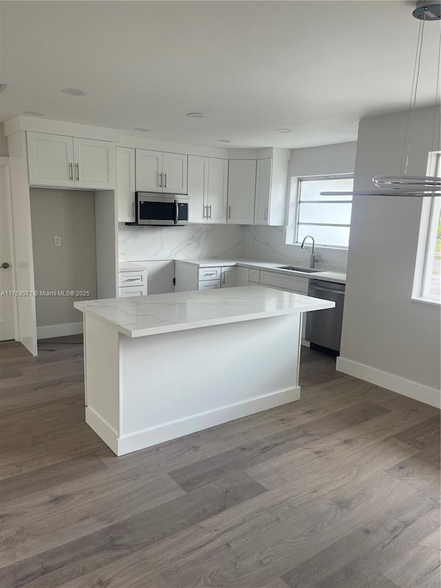 kitchen featuring pendant lighting, appliances with stainless steel finishes, a kitchen island, and white cabinets