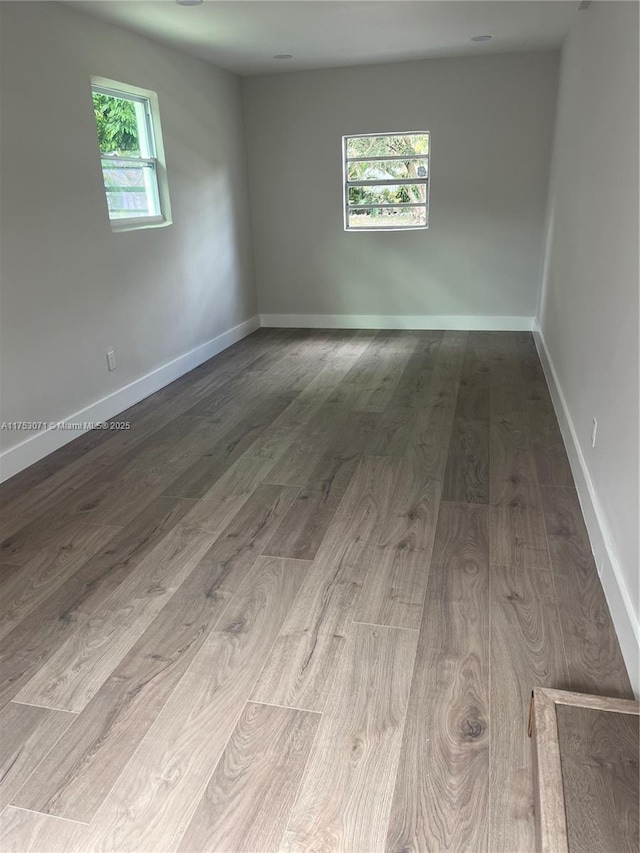 empty room with plenty of natural light, baseboards, and wood finished floors