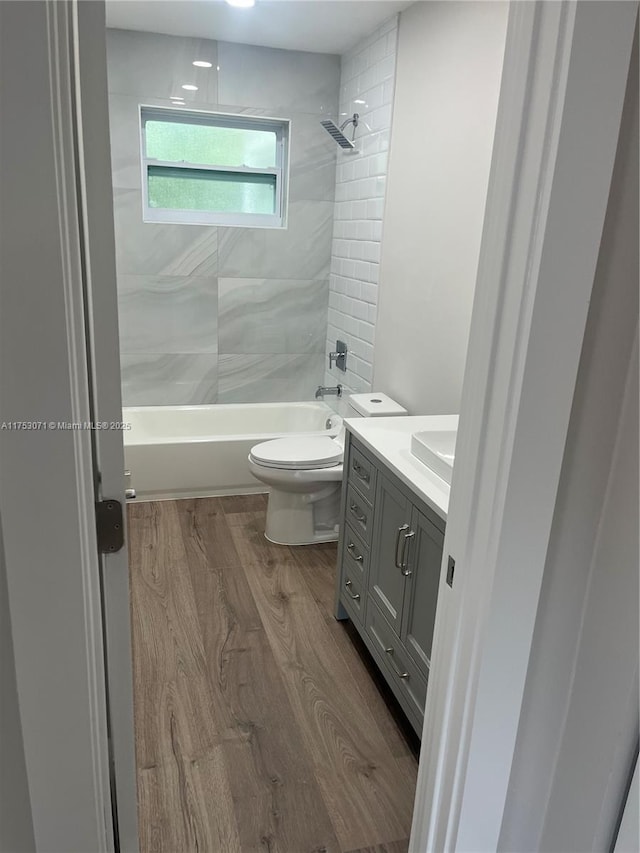 bathroom with toilet, shower / bath combination, wood finished floors, and vanity