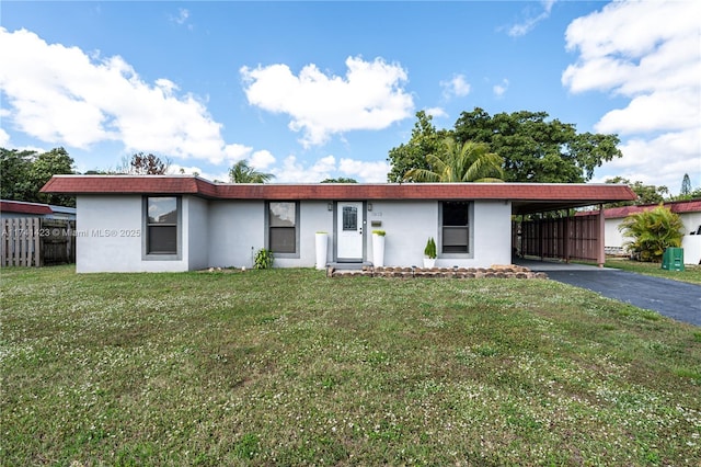 ranch-style home with driveway, stucco siding, a carport, and a front yard