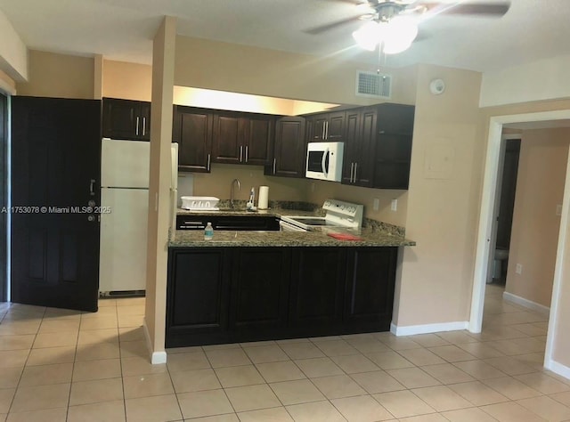 kitchen with stone counters, light tile patterned floors, visible vents, a sink, and white appliances