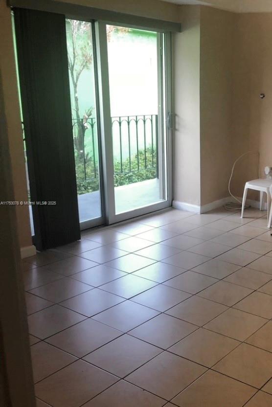 doorway to outside with light tile patterned flooring and baseboards