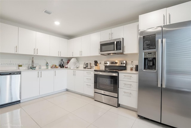 kitchen featuring visible vents, appliances with stainless steel finishes, light countertops, white cabinetry, and a sink