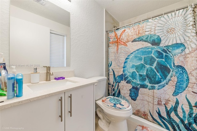 full bath featuring toilet, vanity, a textured ceiling, and a textured wall