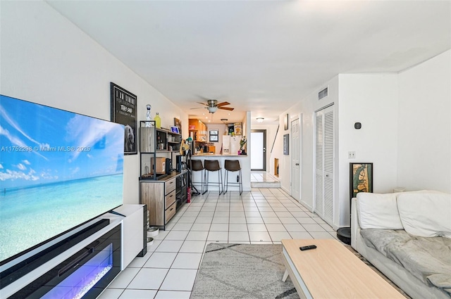 living area featuring light tile patterned floors, ceiling fan, and visible vents