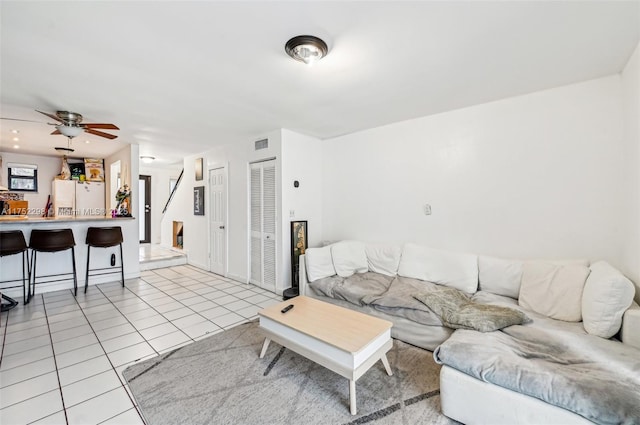 living area with light tile patterned floors, stairway, visible vents, and a ceiling fan