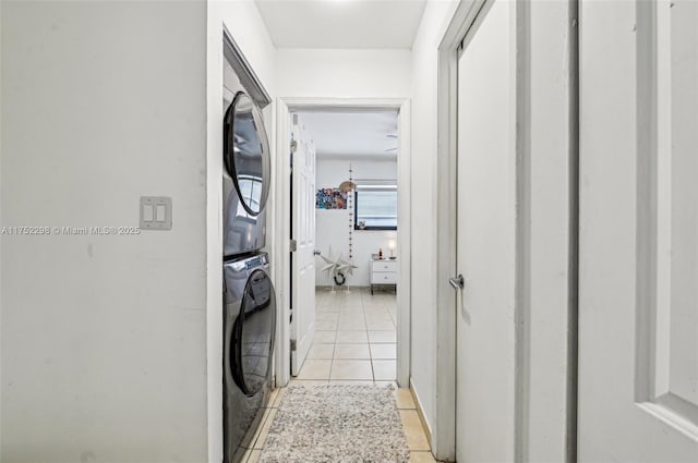 washroom featuring stacked washing maching and dryer, laundry area, and light tile patterned flooring