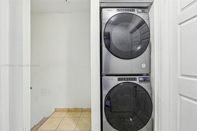 clothes washing area featuring laundry area, stacked washer / dryer, and light tile patterned flooring