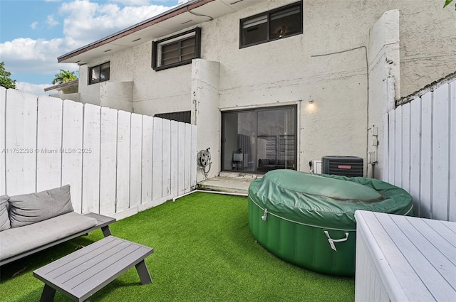 rear view of house featuring a yard, central AC, fence, and stucco siding