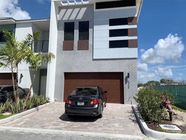 view of front of house featuring brick siding, an attached garage, and decorative driveway