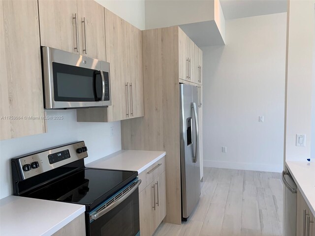 kitchen with light countertops, modern cabinets, light brown cabinetry, and stainless steel appliances
