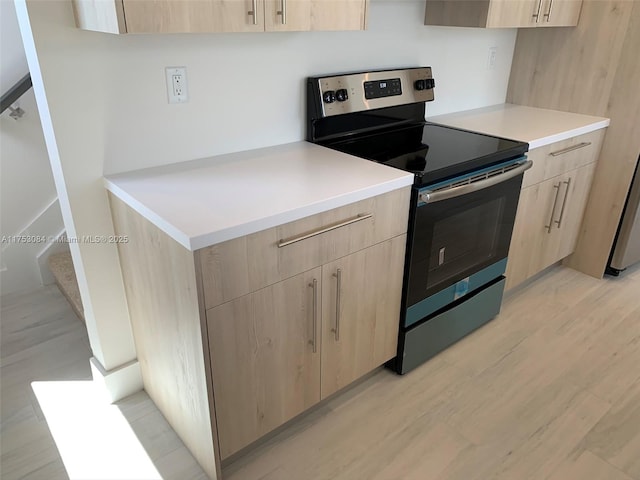 kitchen featuring light brown cabinetry, light countertops, light wood-style flooring, stainless steel electric stove, and modern cabinets