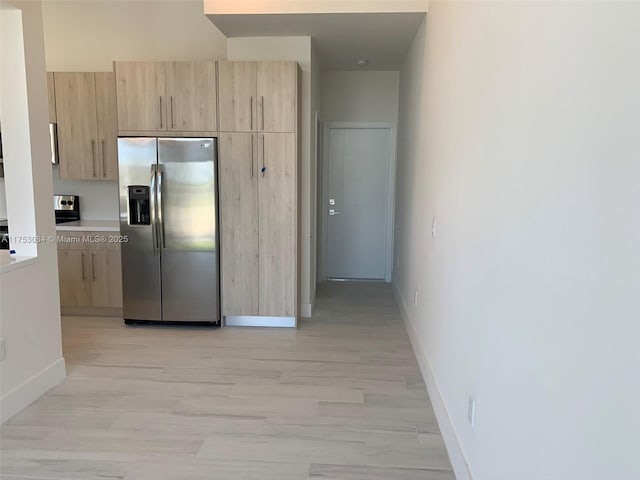 kitchen with stainless steel fridge, baseboards, and light brown cabinets