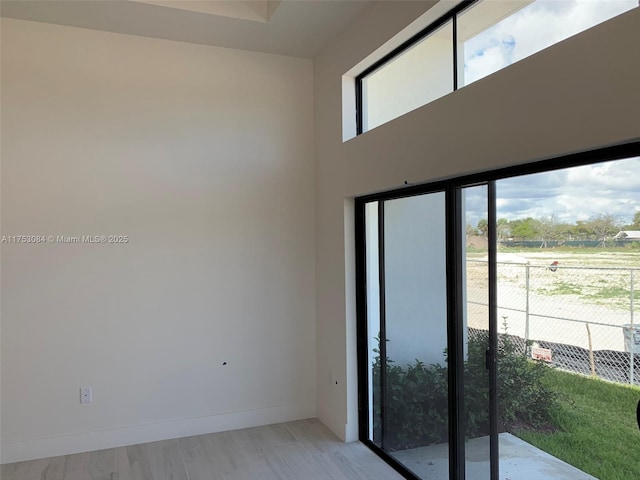 spare room with baseboards and light wood-style floors