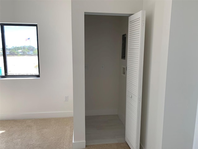 hallway featuring baseboards and light carpet