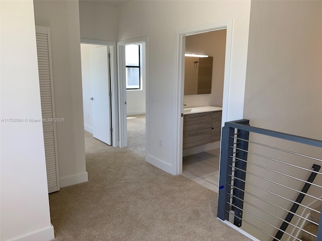 hallway featuring baseboards, carpet flooring, and an upstairs landing