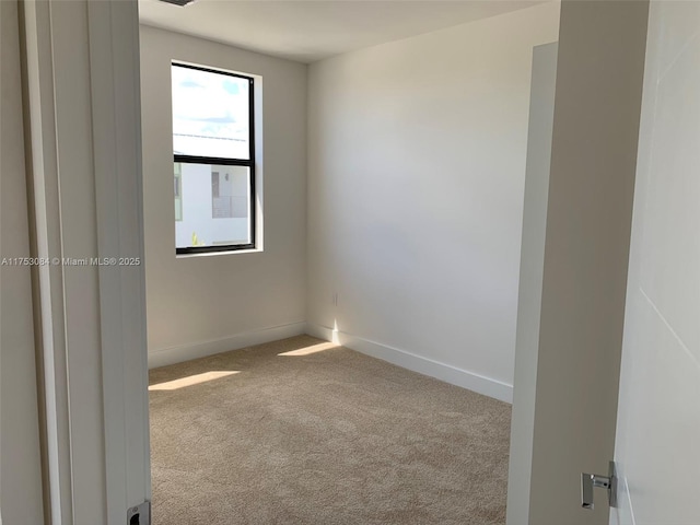 spare room featuring carpet floors and baseboards