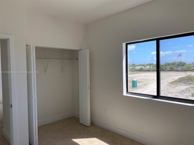 unfurnished bedroom featuring carpet floors, baseboards, and a closet