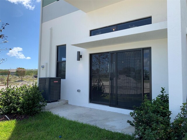 view of exterior entry with cooling unit and stucco siding