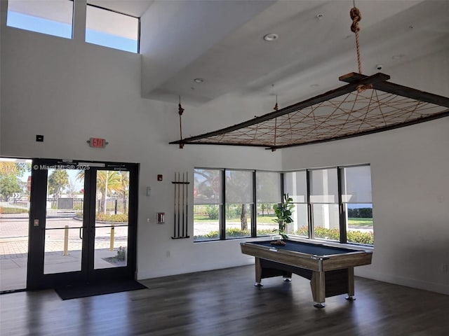 game room featuring baseboards, wood finished floors, and a towering ceiling