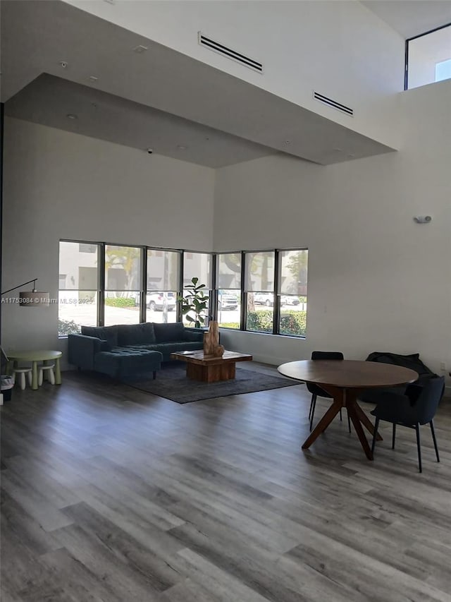 living area featuring wood finished floors, a high ceiling, and visible vents