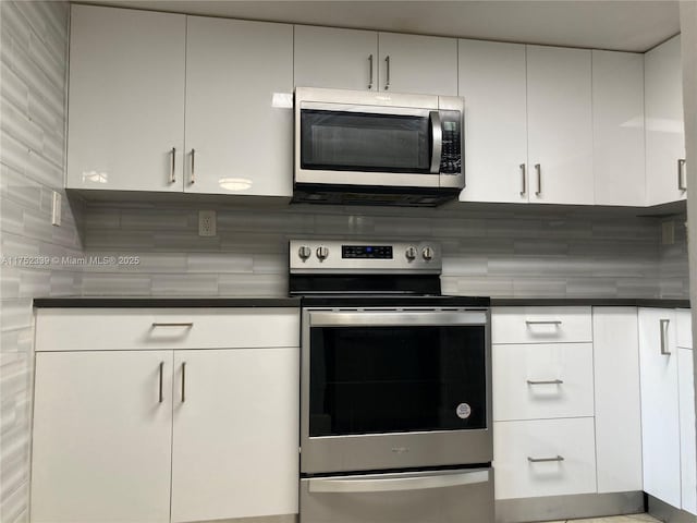 kitchen with dark countertops, appliances with stainless steel finishes, and white cabinets